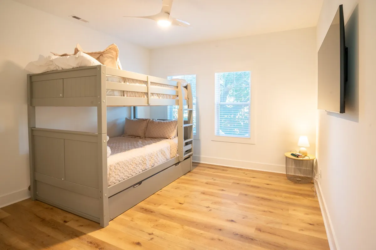 A cozy bunk suite with a bunk bed, large windows streaming with sunlight, and a flat screen TV. The space is bright and family-friendly, ideal for kids or larger groups.