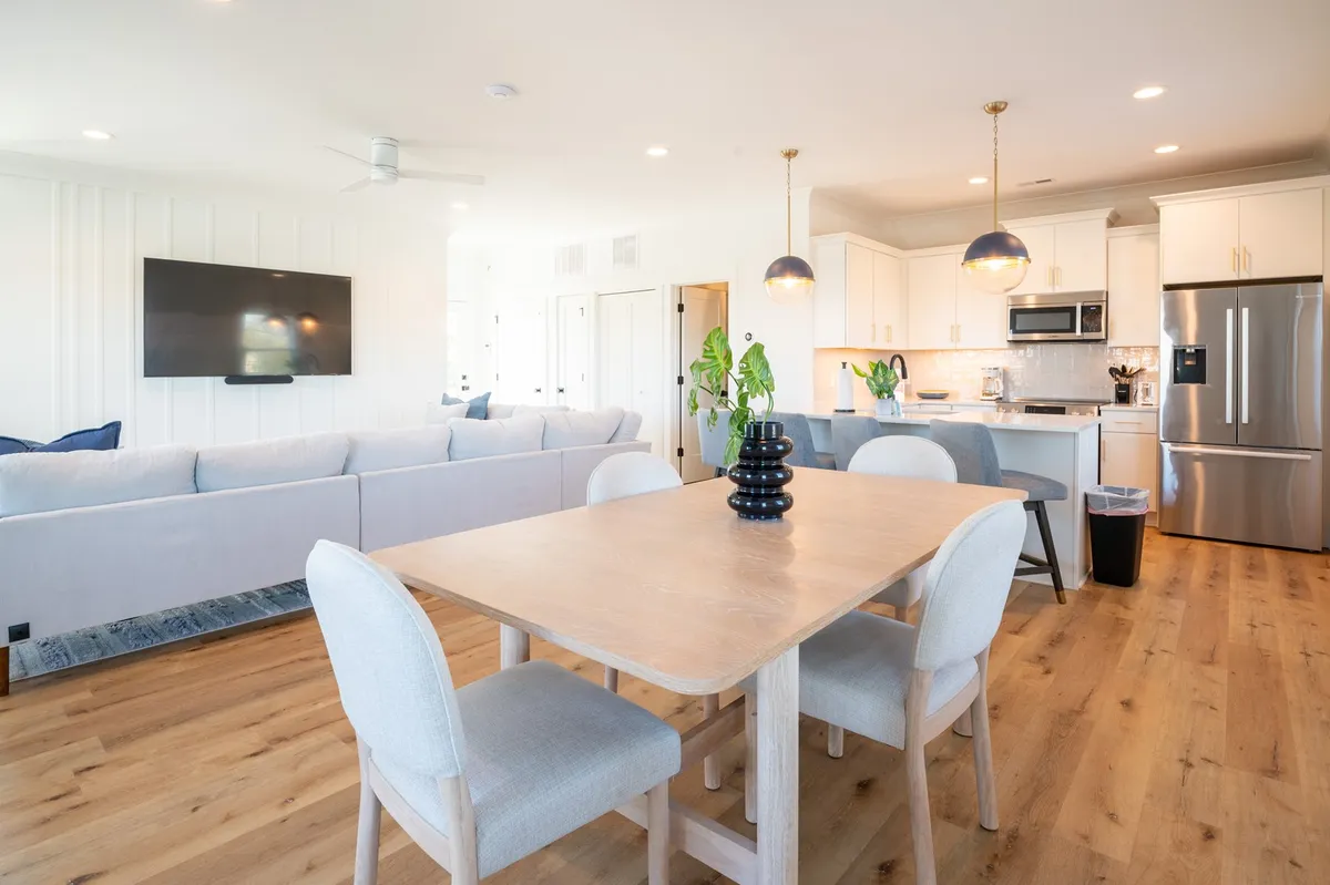 A warm, welcoming scene showing the dining table, sofa, kitchen appliances, and television. The space is arranged for family meals, relaxing with loved ones, and cozy evenings watching television together.