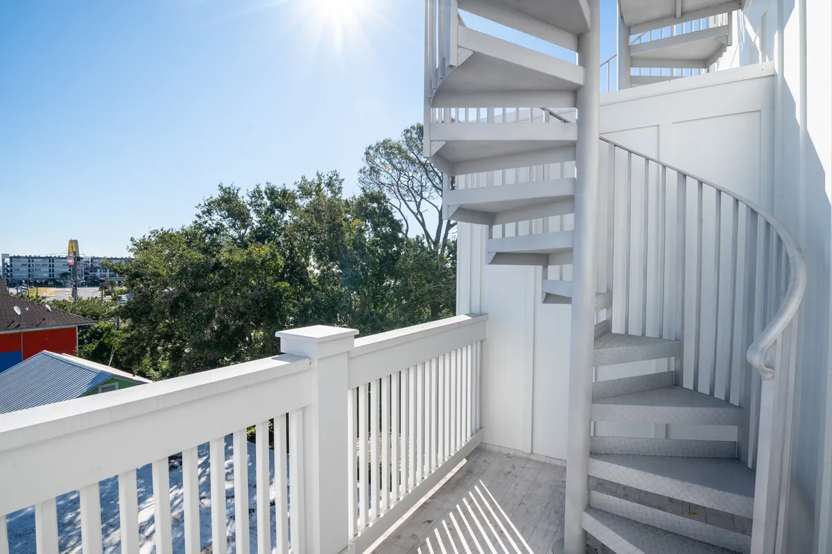 A sunlit exterior featuring a spiral staircase leading to a rooftop area, with railings and sunlight emphasizing the elevation and open-air ambiance. The photo hints at panoramic views and the excitement of ascending to a private vantage point.