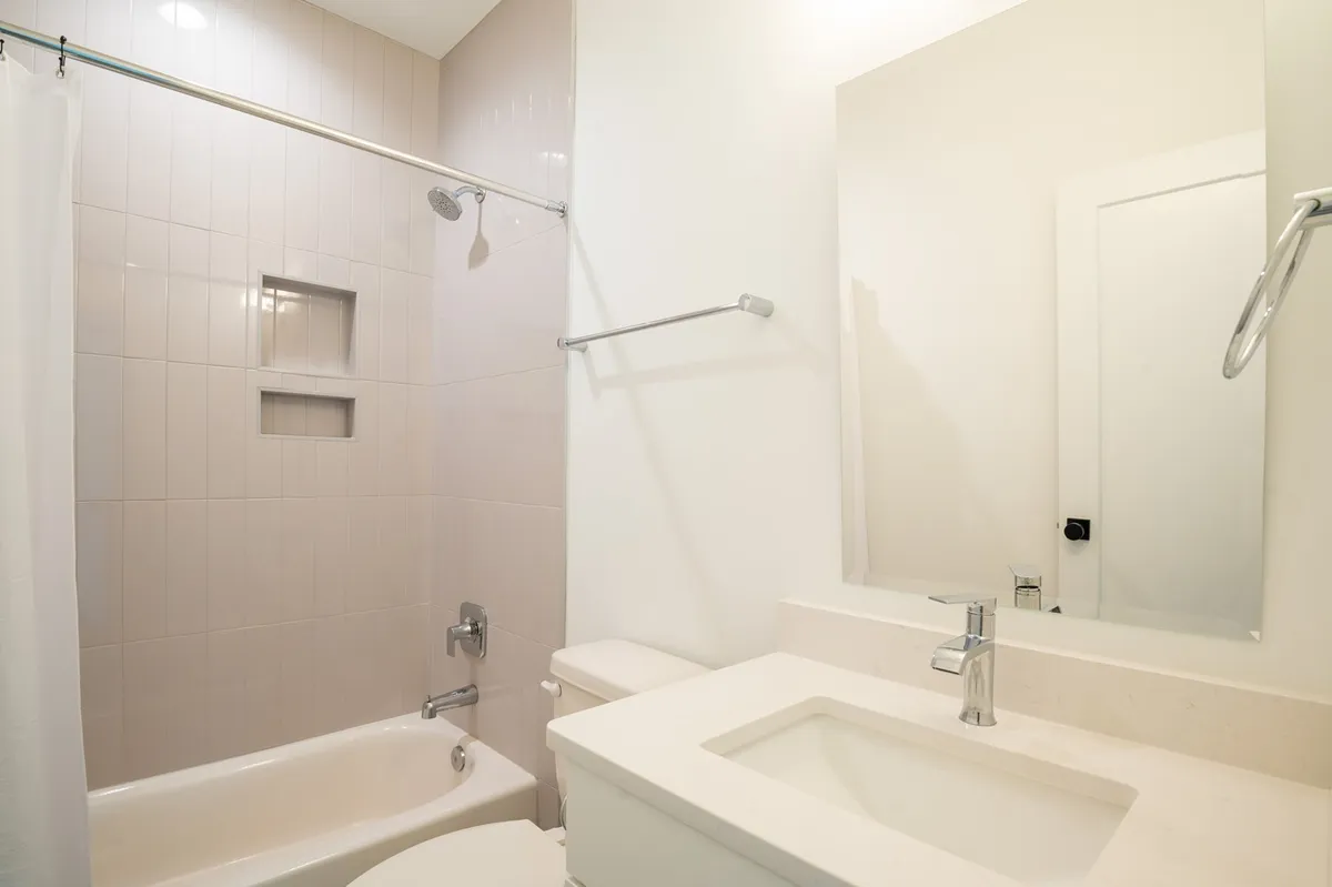 A calm and modern ensuite bathroom featuring a large sink, elegant bathtub, and well-lit mirror. The space radiates tranquility and spa-like comfort.