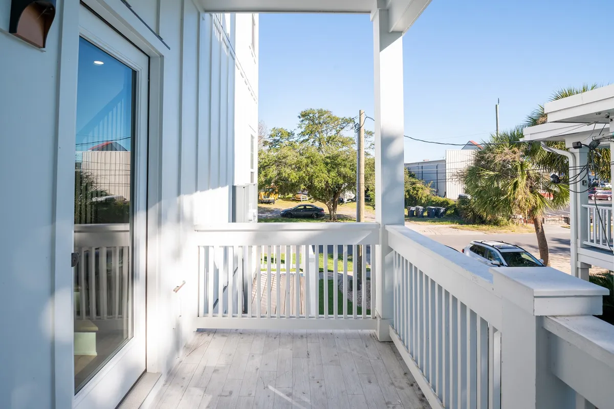 A relaxed exterior balcony scene showing a railing with views of the surrounding urban area and blue sky, suggesting a perfect spot for morning coffee or evening cocktails.
